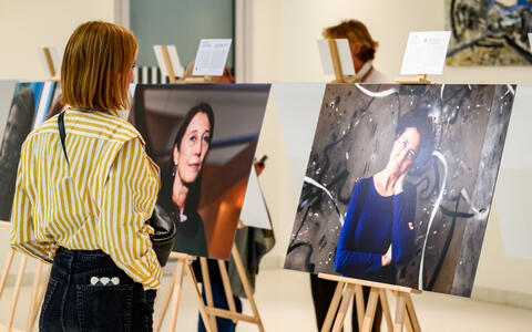 Frau schaut auf ein Porträt in einer Galerie